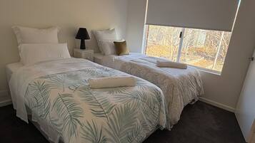 Un dormitorio con dos camas, una mesita de noche, una lámpara y una ventana con vistas.