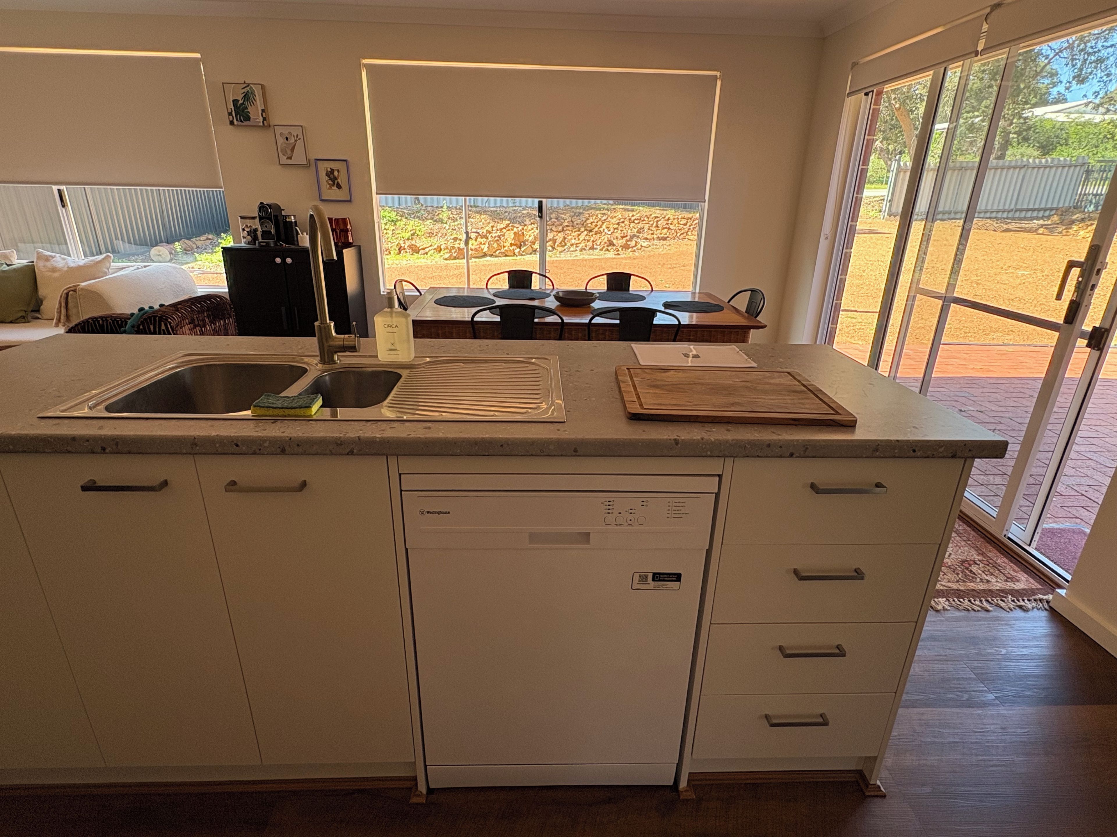 Una cocina con lavavajillas integrado, un lavabo y una zona de comedor con mesa y sillas.
