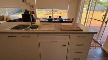 Una cocina con lavavajillas integrado, un lavabo y una zona de comedor con mesa y sillas.