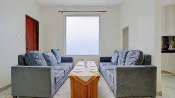 Una sala de estar moderna con dos sofás grises, una mesa de centro de madera y un ventanal grande.