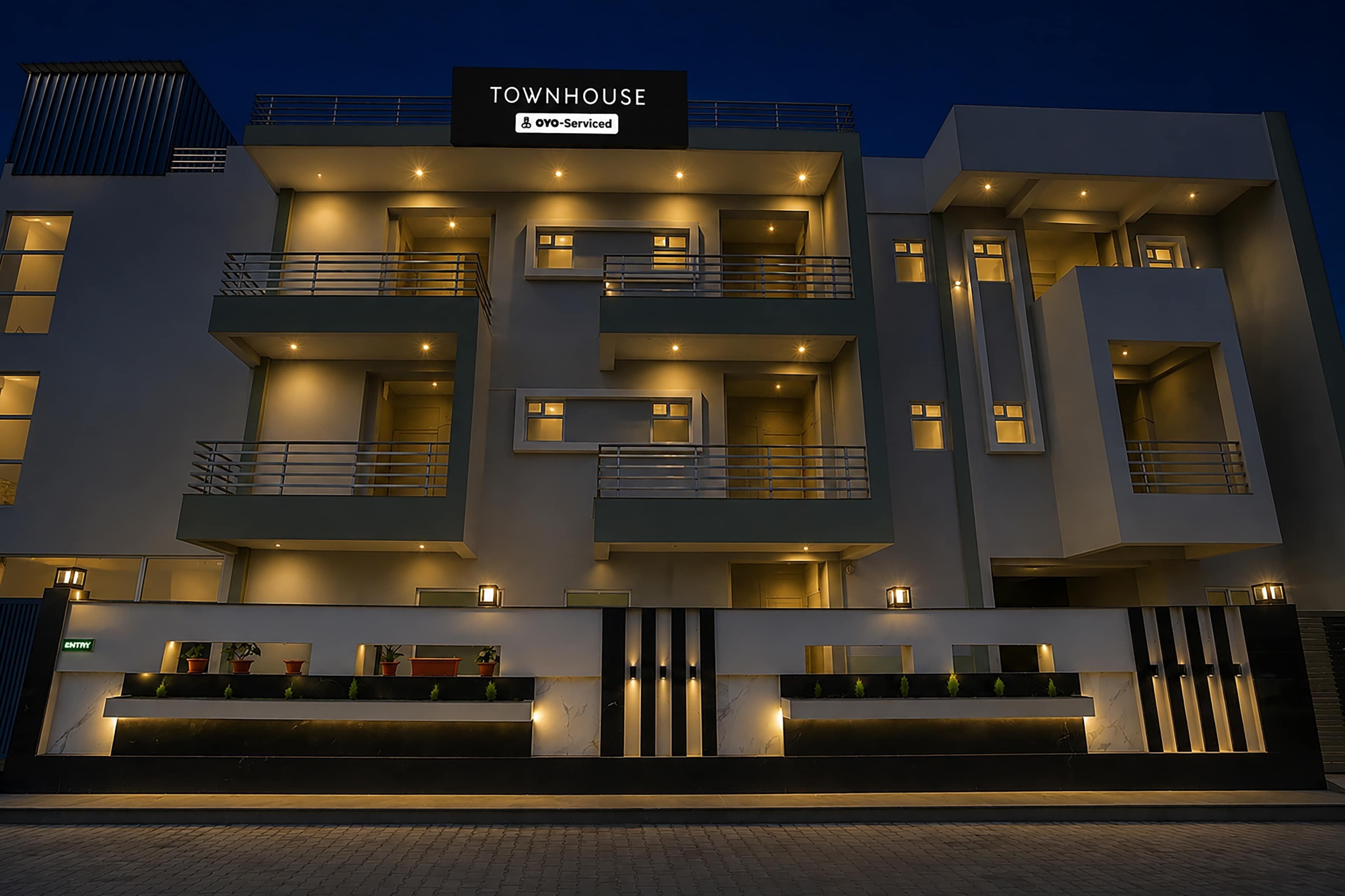 A multi-story hotel with a modern design, featuring balconies, a reception area, and a sign indicating it is serviced by OYO.