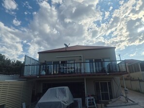 Ein zweistöckiges Haus mit einem Balkon, einer Satellitenschüssel und einem überdachten Carport.