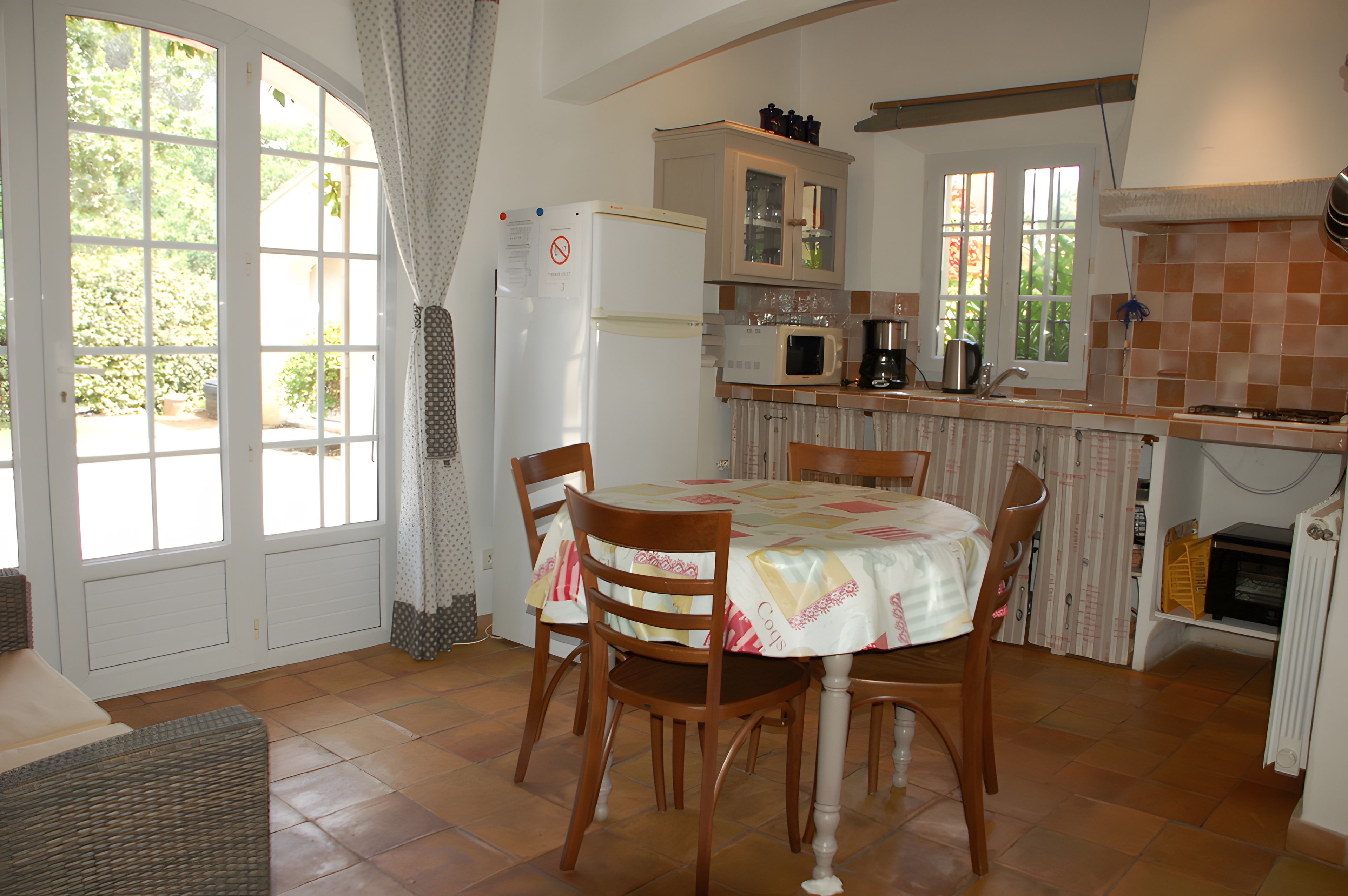 A kitchen with a dining table, chairs, a refrigerator, a microwave, and a coffee maker.