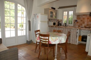 Una cocina con mesa, sillas, refrigerador, microondas y cafetera.
