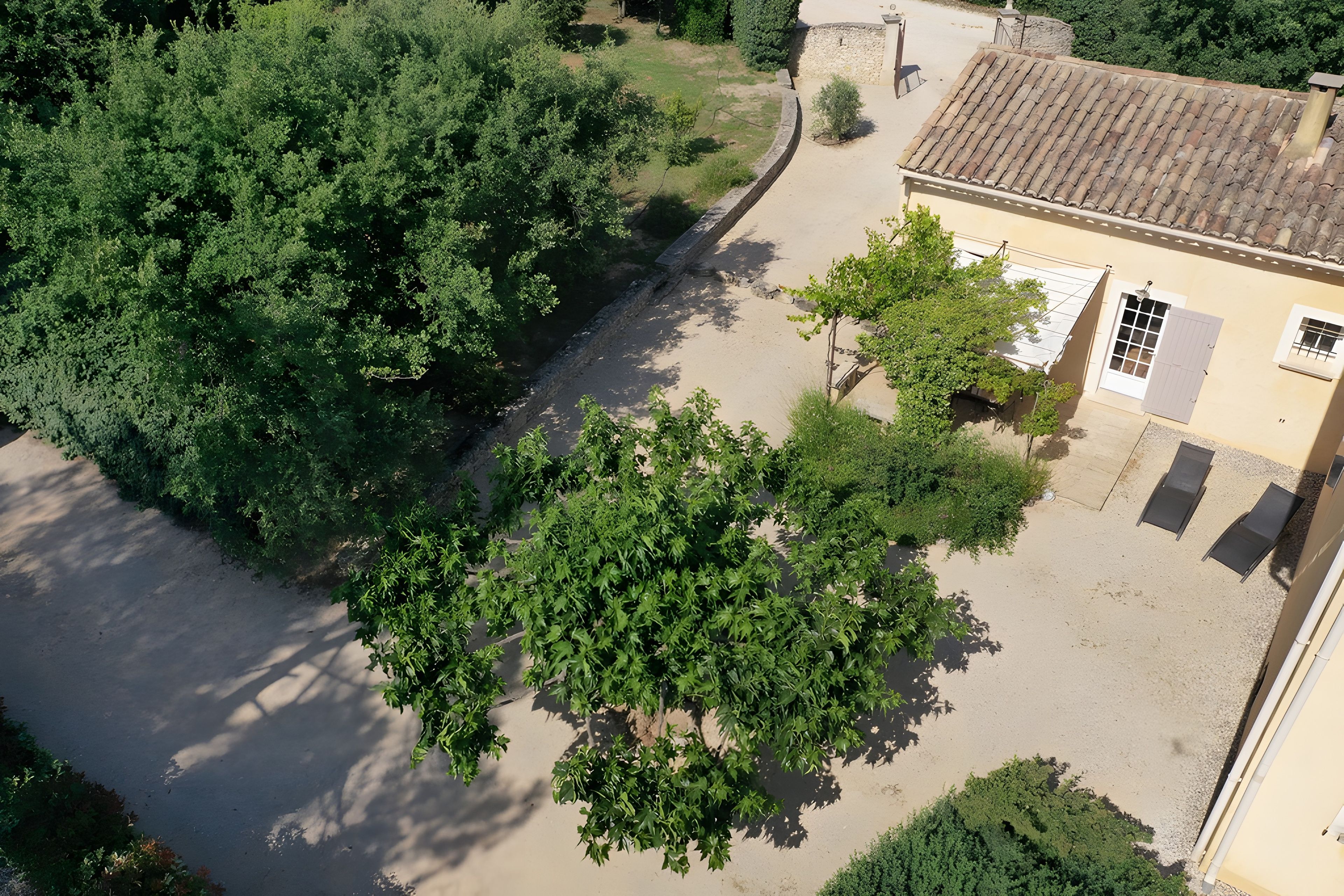 A building with a tiled roof, a paved driveway, and surrounding greenery.