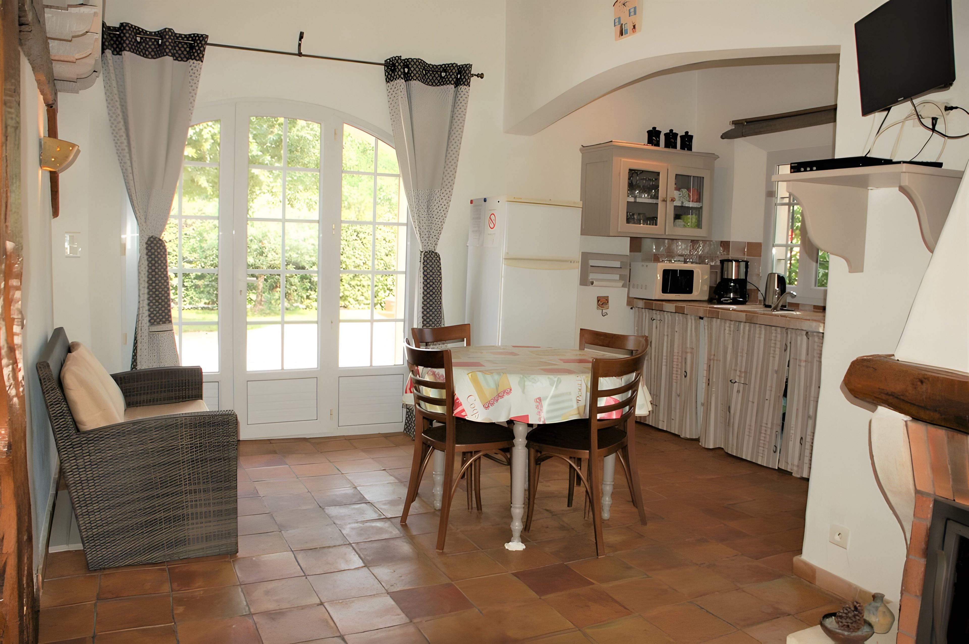 A dining area with a table and chairs, a kitchen with cabinets and appliances, and a fireplace.