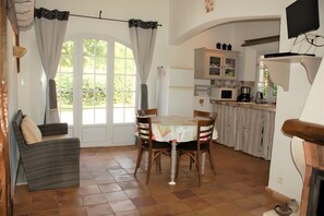 Un espace repas avec une table et des chaises, une cuisine équipée d’armoires et d’appareils électroménagers, et une cheminée.
