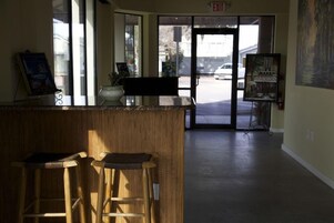 Un área de recepción con un mostrador de madera, dos taburetes de bar y una puerta que da al exterior.