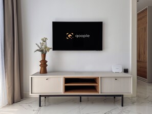 Ein modernes Wohnzimmer mit einem an der Wand befestigten Flachbildfernseher, einer Holzkabine mit Schubladen und einer kleinen Pflanze auf der Kabine.