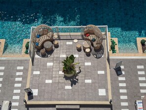 Una terraza en la azotea con piscina, mobiliario de mimbre y plantas en macetas.