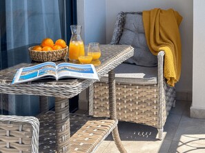 Ein Korbtisch mit einem Buch, einer Orangenschale und einem Glas Orangensaft.