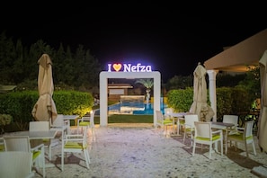 An outdoor seating area with tables and chairs, a pool, and a sign that reads 'I ♥ Nefza'. - amine saidi (Nefza)