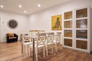 A dining area with a round table and chairs, a clock on the wall, and a cabinet with glass doors. - Spacious flat in  centre of the Barrio del Oeste (Salamanca)