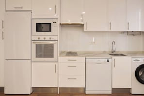 Eine moderne Küche mit Kühlschrank, Mikrowelle, Backofen, Geschirrspüler und Waschmaschine.