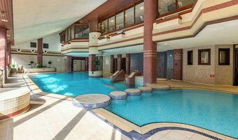 Una piscina interior con varios niveles, una escalera central y suelo de baldosas.