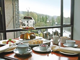 Una mesa servida con servicio de té y pasteles, con vistas panorámicas a través de un amplio ventanal.