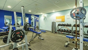 A gym with weightlifting equipment, benches, and a wall-mounted rack of dumbbells. - Whitewater Hotel and Spa (Ulverston)