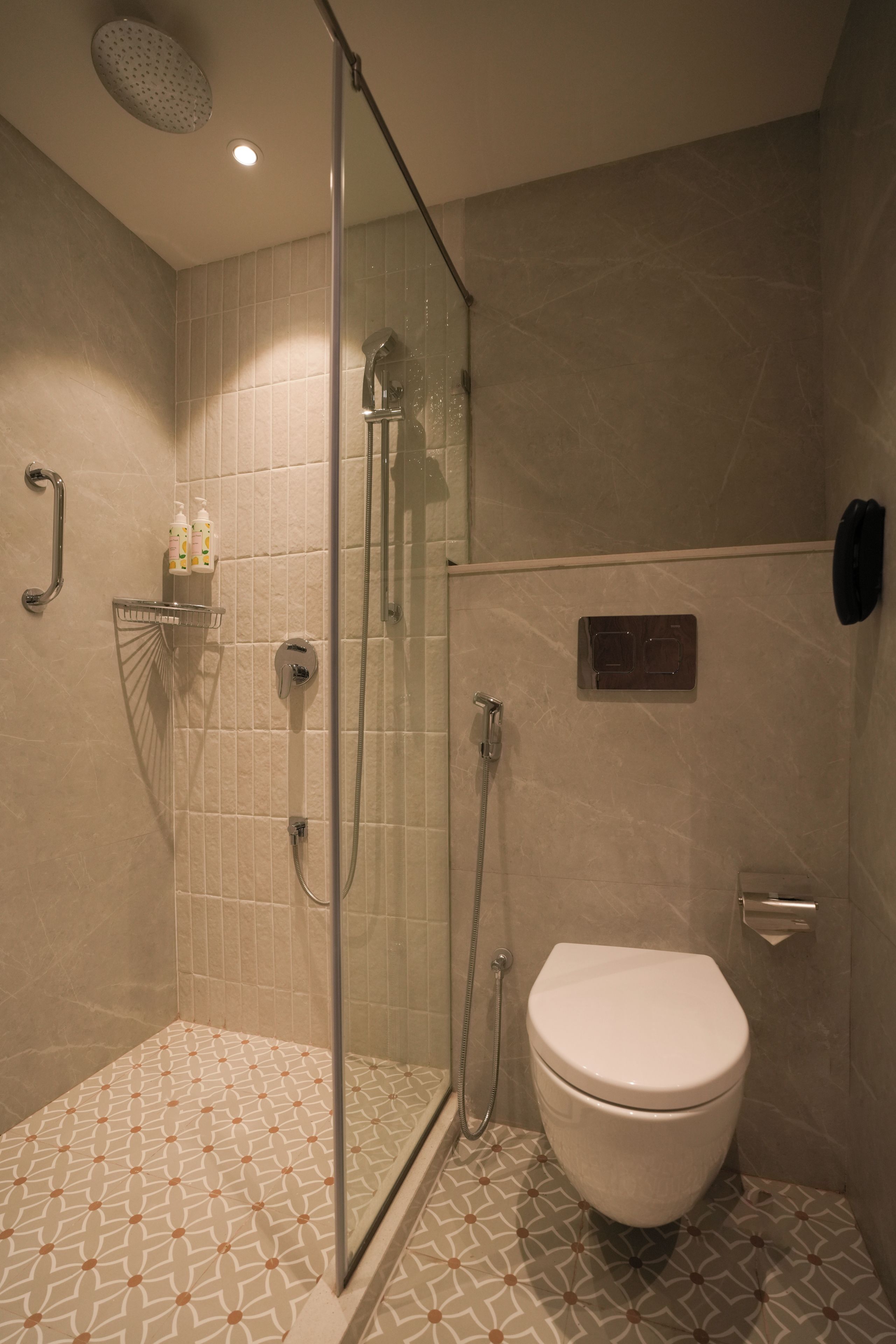 A modern bathroom with a glass-enclosed shower, a toilet, and a hand dryer.