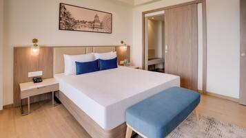 Une chambre d’hôtel moderne avec un grand lit, des tables de chevet, une lampe de chevet, une petite table et un grand miroir.