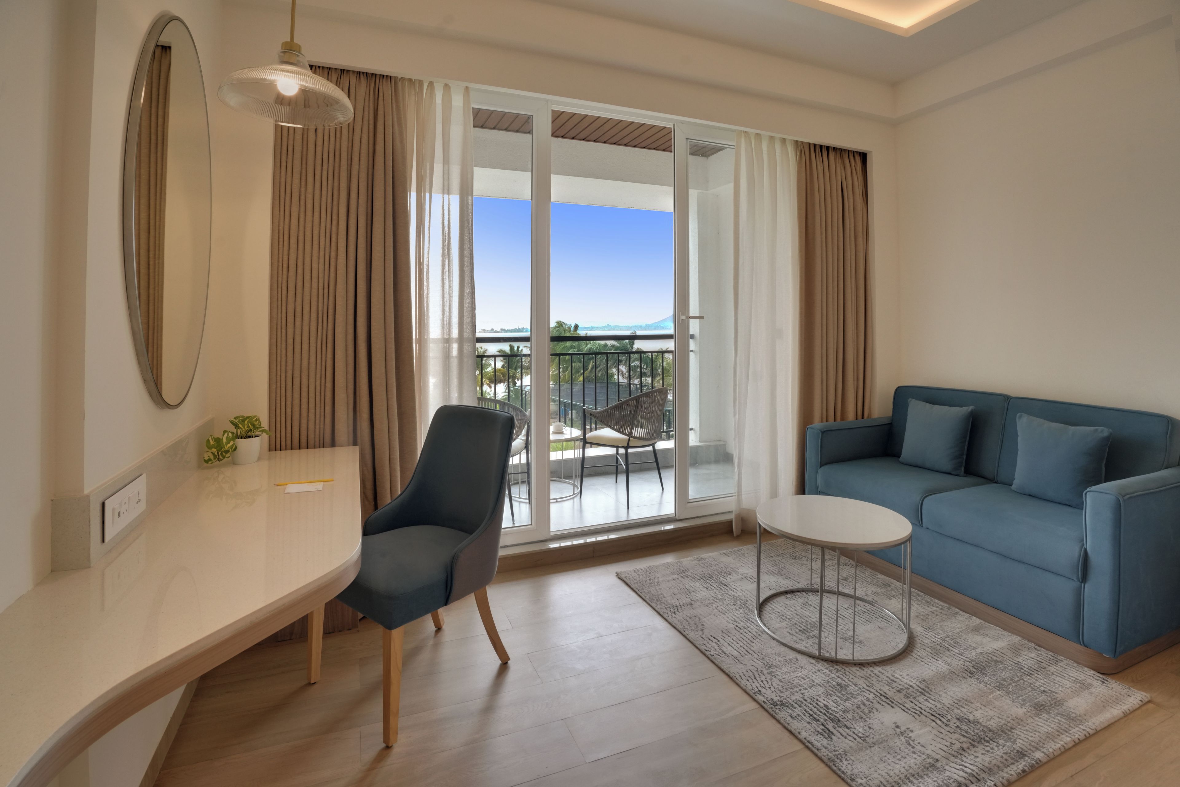 A modern living room with a sofa, a chair, a small table, and a view of the outdoors through large glass doors.