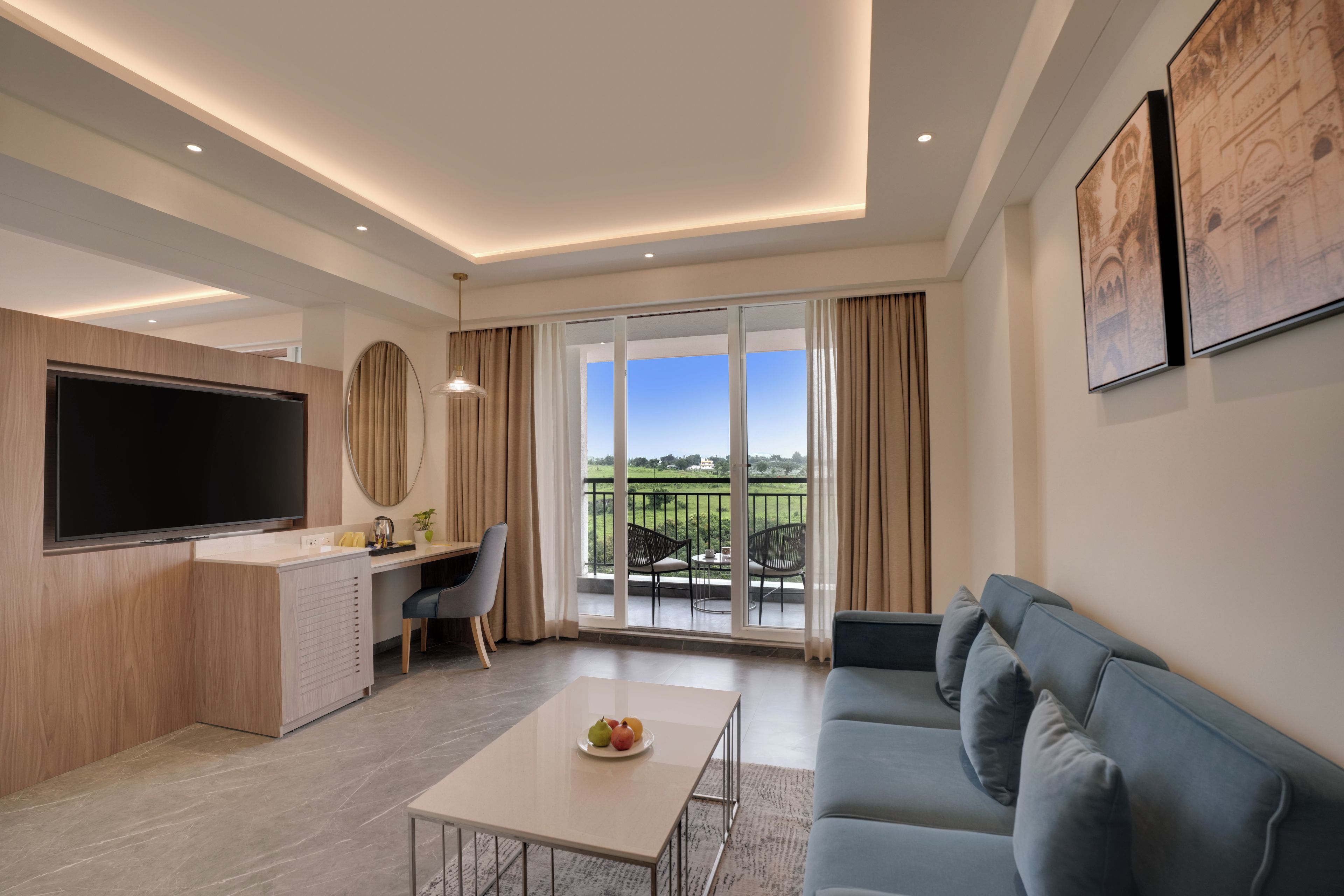Una sala de estar moderna con televisor de pantalla plana, un sofá, una mesa de comedor con fruta y un balcón con vistas.