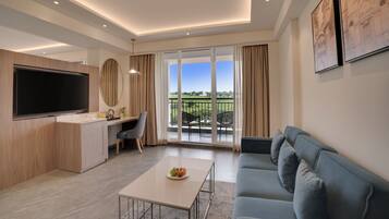 Una sala de estar moderna con televisor de pantalla plana, un sofá, una mesa de comedor con fruta y un balcón con vistas.