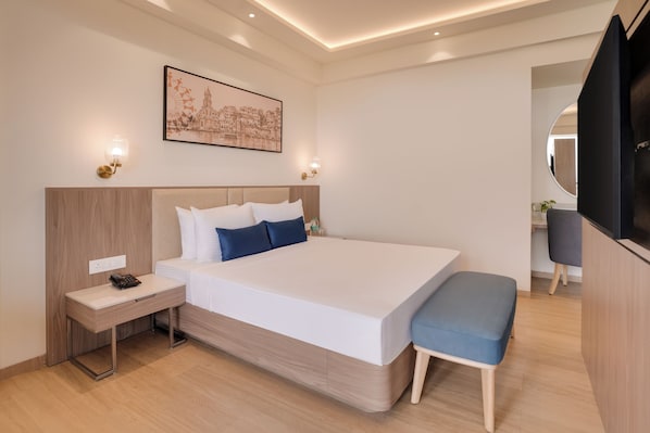A modern hotel room with a large bed, bedside tables, a desk, and a TV. - Lemon Tree Resort, Nashik (Nashik)