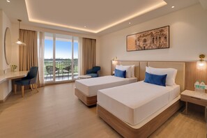 A hotel room with two beds, a desk, a chair, a balcony with a view, and a painting on the wall. - Lemon Tree Resort, Nashik (Nashik)
