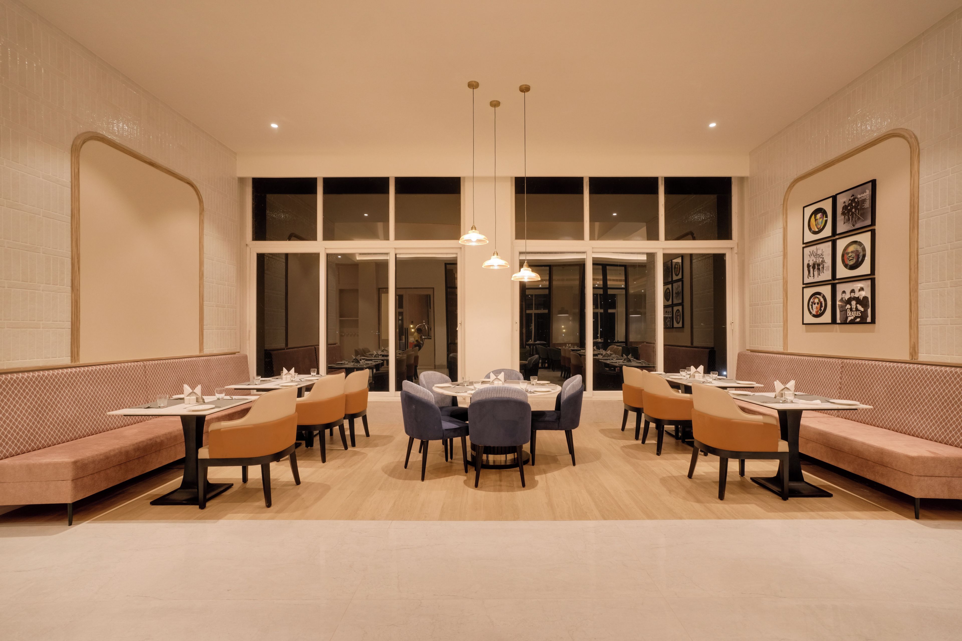 Un restaurante con cabinas y mesas, amplios ventanales e iluminación colgante.