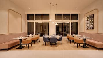 Un restaurante con cabinas y mesas, amplios ventanales e iluminación colgante.