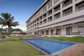 A multi-story hotel with a swimming pool, outdoor seating, and palm trees. - Lemon Tree Resort, Nashik (Nashik)