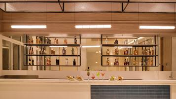 Zona de bar con estantes llenos de botellas de licores y una barra con comida y bebidas.