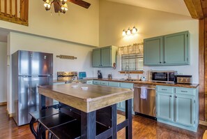 A kitchen with a stainless steel refrigerator, a wooden table, and light blue cabinets. - Canopy View Lodge - Awesome Mountain Views, Hot Tub!!! (Sevierville)