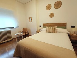 Ein Hotelzimmer mit einem Bett, einem Sessel, einem Tisch, einem Spiegel und Wanddekoration.