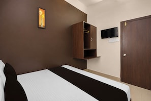Habitación de hotel con cama, armario, televisión e interruptor de luz en la pared.