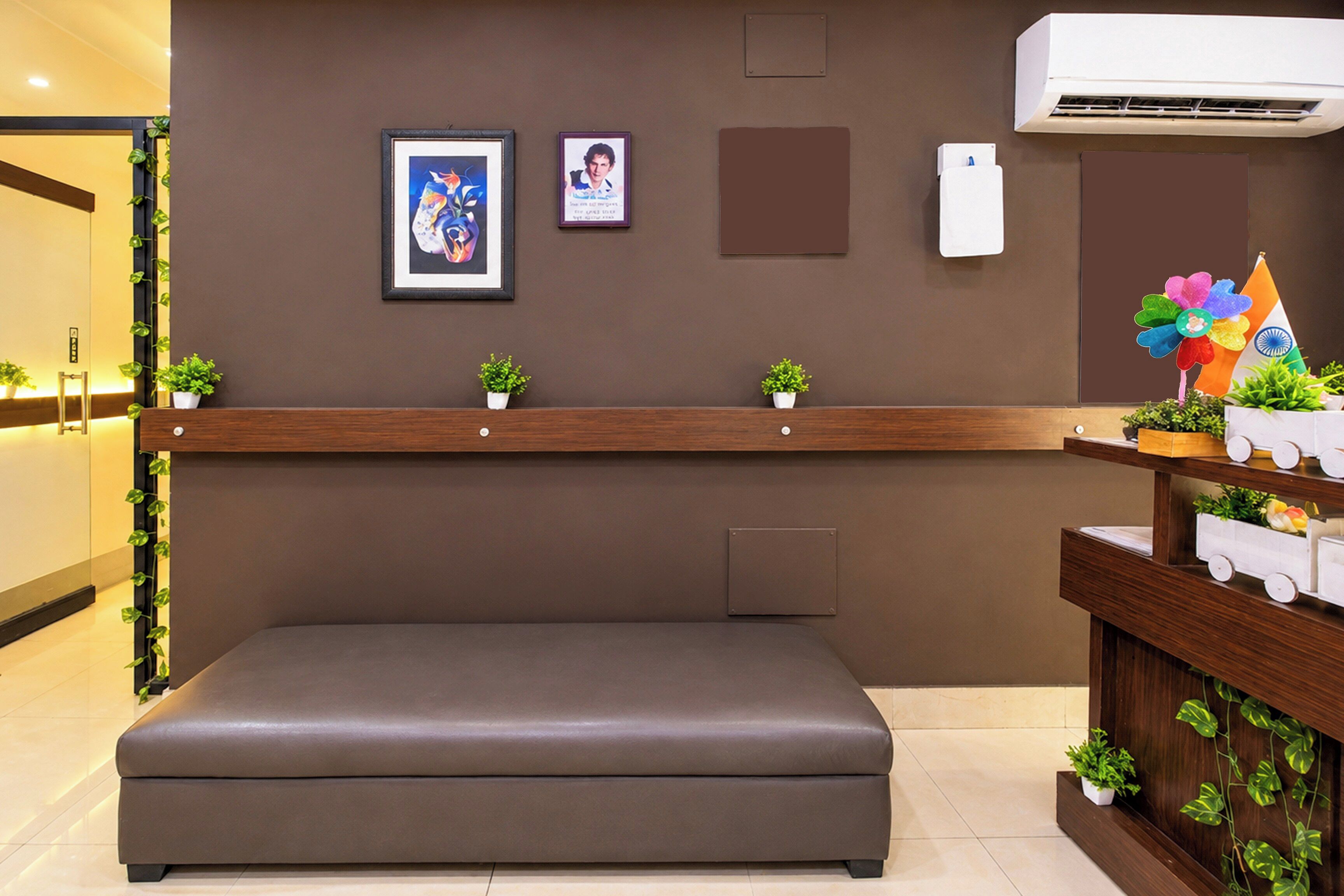 A reception area with a bench, framed artwork, a potted plant, and a wall-mounted air conditioner.