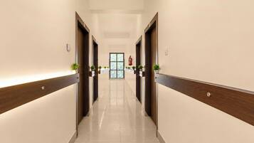 A corridor with wooden doors, potted plants, and a fire extinguisher on the wall.