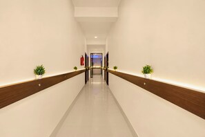 Un pasillo largo y estrecho con suelo de madera y paredes blancas, que conduce a una puerta al final.