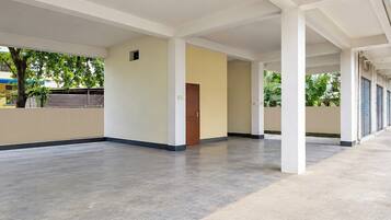 A spacious indoor area with a concrete floor, white walls, and a wooden door.