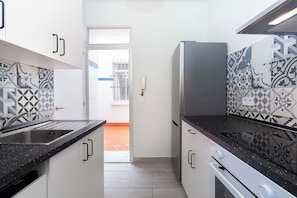 A kitchen with white cabinets, a black countertop, and patterned tile backsplash. - Spacious 5-bedroom apartment next to the Cathedral (Sevilla)