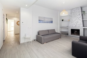 A modern living room with a grey sofa, a fireplace, and a hanging light fixture. - Spacious 5-bedroom apartment next to the Cathedral (Sevilla)