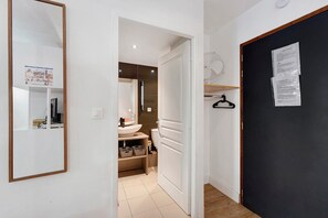 A hallway leading to a bathroom with a toilet, sink, and storage bins.