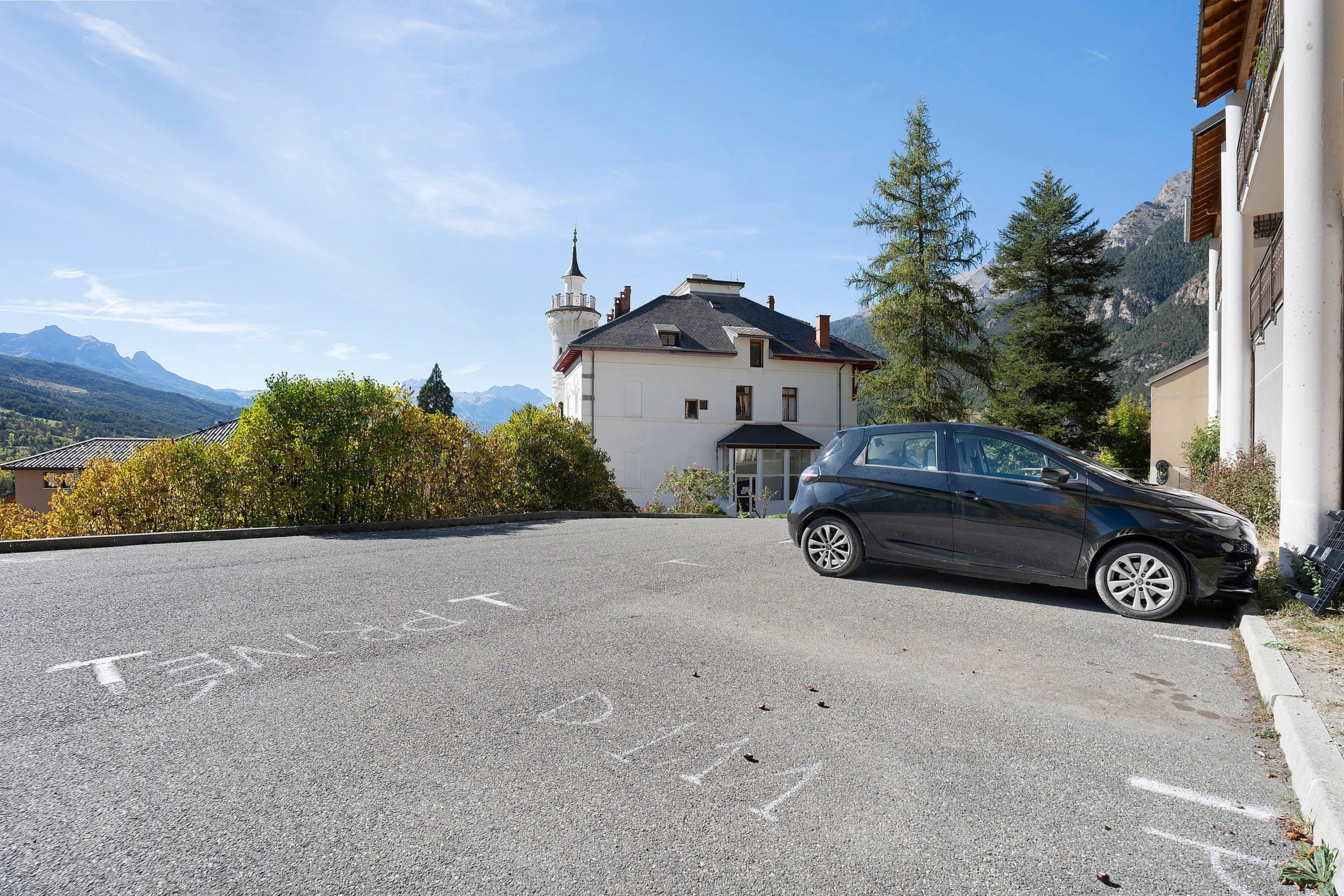 Un'auto parcheggiata in vialetto, con un edificio sullo sfondo.