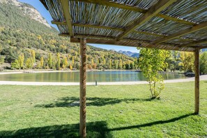 A wooden pergola structure with a view of a lake and mountains in the background.