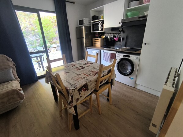 Una cocina compacta con lavadora, una mesa de comedor con sillas y vistas al exterior.