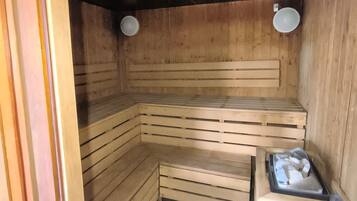 Een sauna met houten banken en een klein tafeltje met handdoeken.