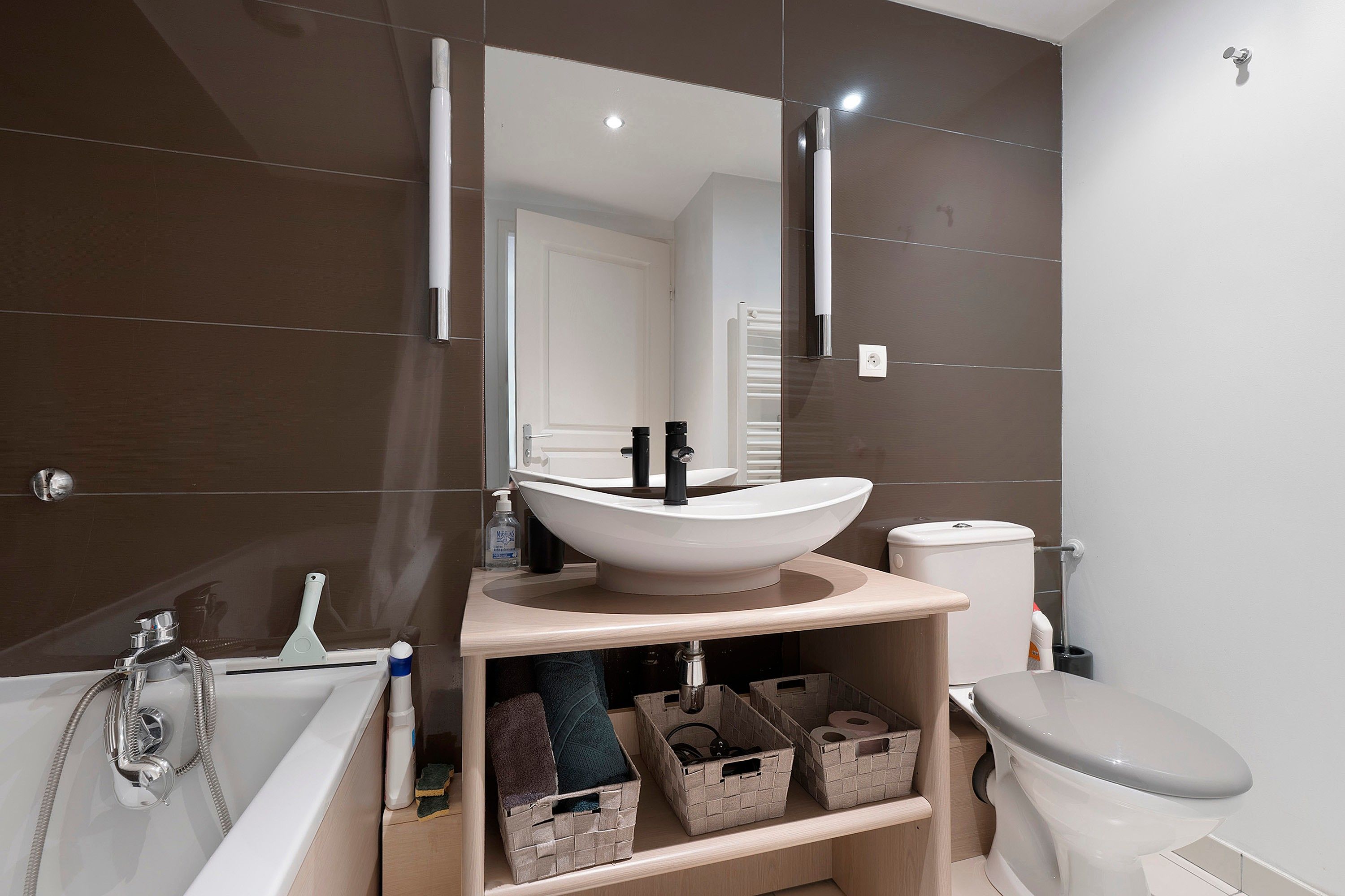 A modern bathroom with a vessel sink, a toilet, a bathtub, and a mirror above the sink.