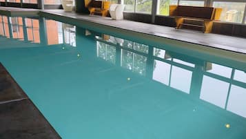 An indoor swimming pool with a clear view of mountains through large windows.