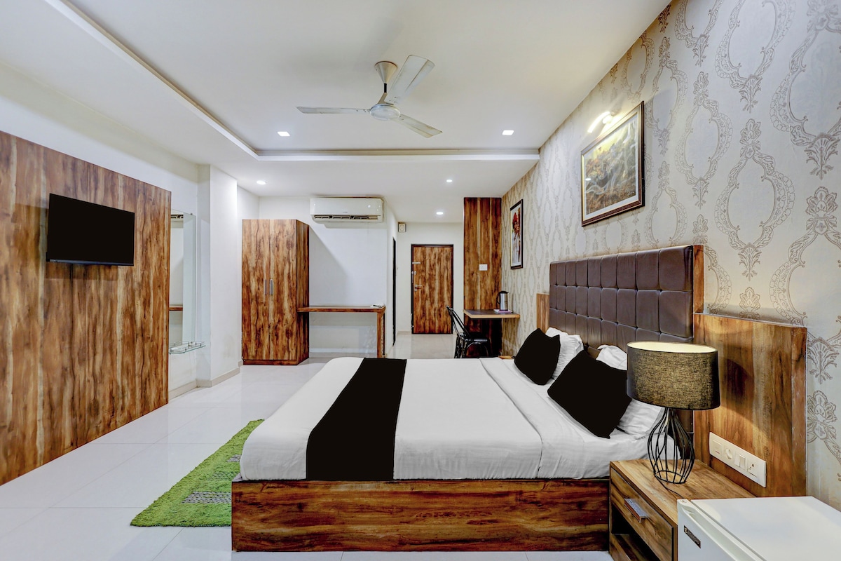 A modern bedroom with a large bed, a ceiling fan, an air conditioning unit, and a television mounted on the wall.