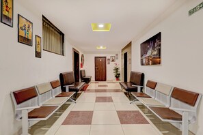 A hallway with two rows of waiting chairs, a door at the end, and a ceiling light.